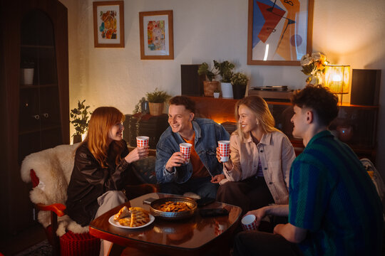 Friends enjoy drinks and snacks in a cozy living room, creating warmth and comfort