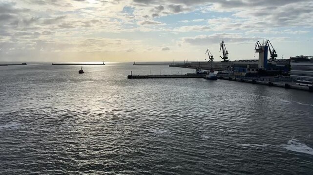 Seaport with berths and port cranes from moving vessel
