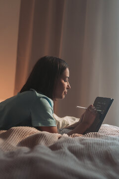 Artist Sketches Late, Female Illustrator Drawing With Stylus In Comfortable Nighttime Environment