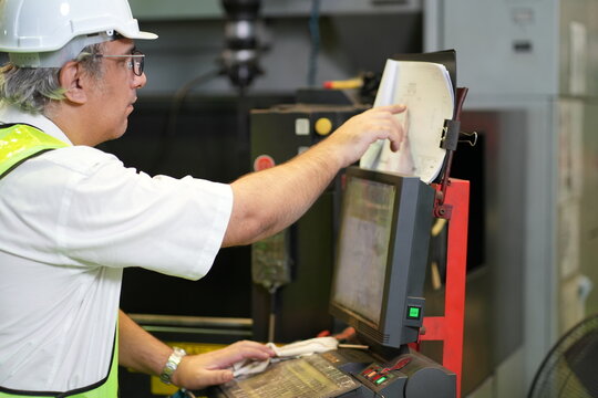 Male industrial worker operating machine control panel in modern manufacturing factory
