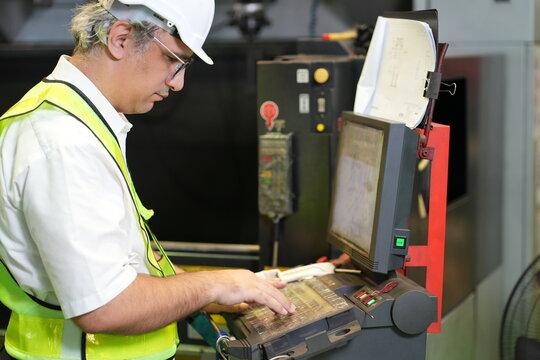 Male industrial worker operating machine control panel in modern manufacturing factory