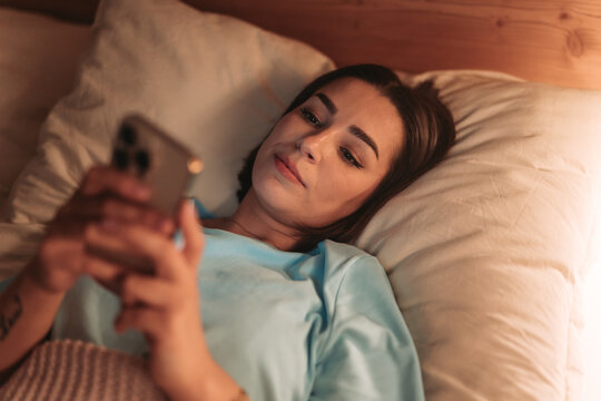Woman Meditates With App At Night, Calm Evening Practice Using Phone For Mindfulness And Relaxation