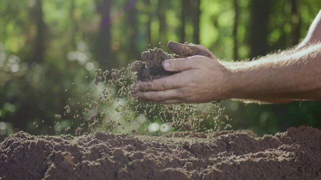 Close-up of clay and dirt. Soil ready for planting. Cultivated earth in hands. Fertile ground close view. Sustainable land concept. Hands pouring soil gently. Falling soil in slow motion.