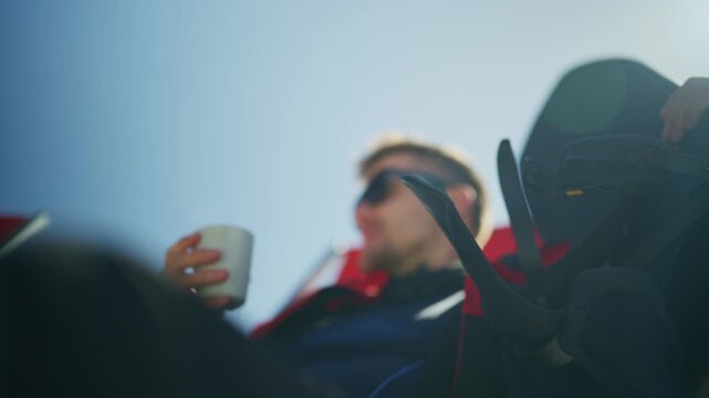 A man in ski gear pauses for a refreshing hot drink on a bright, clear day. He takes a moment to relax and re-energize during his winter sports adventure.