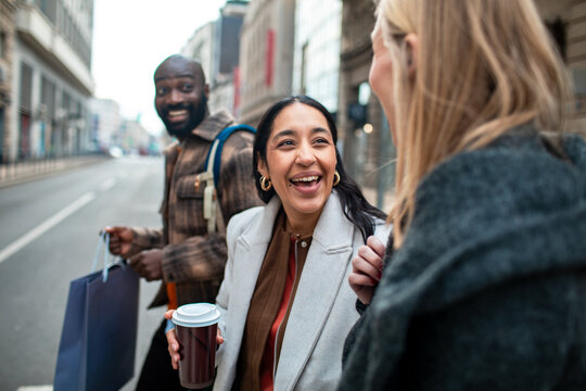 Friends laughing and walking with coffee on city street