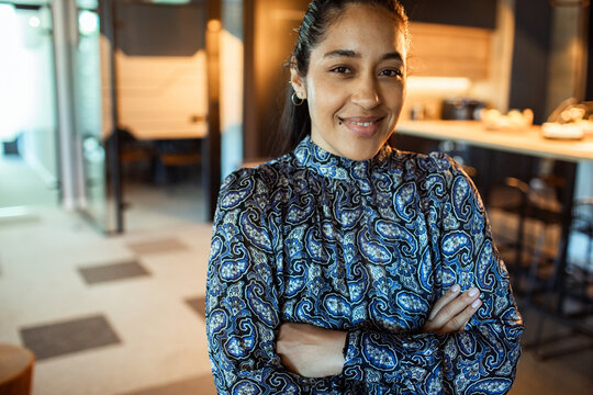 Confident businesswoman with arms crossed in modern office