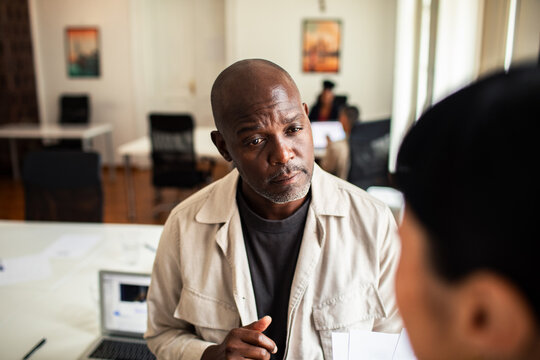 Manager listening to colleague in modern office