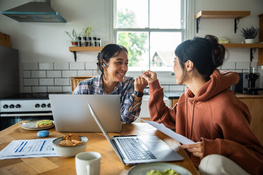 Two women celebrate remote work success in home kitchen