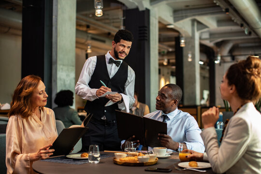 Business colleagues ordering lunch from waiter in modern restaurant