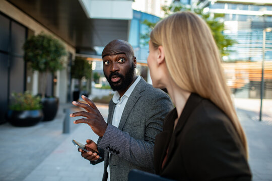 Coworkers react to smartphone news outside office