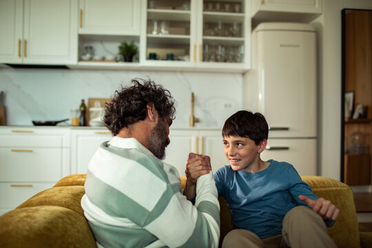 Father and son arm wrestling in home kitchen
