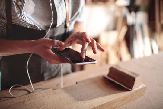 Artisan using smartphone in carpentry workshop