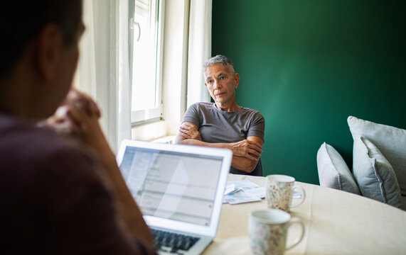 Two people discussing household bills at kitchen table