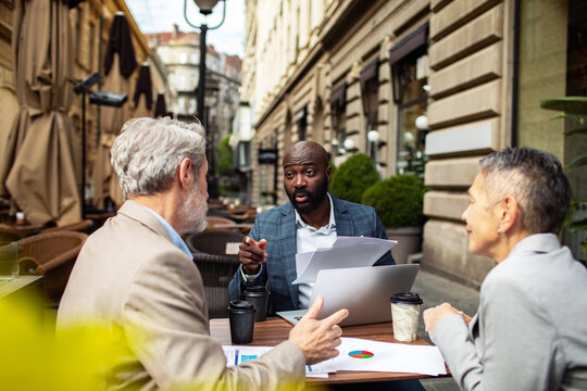 Business professionals discussing financial reports at outdoor cafe
