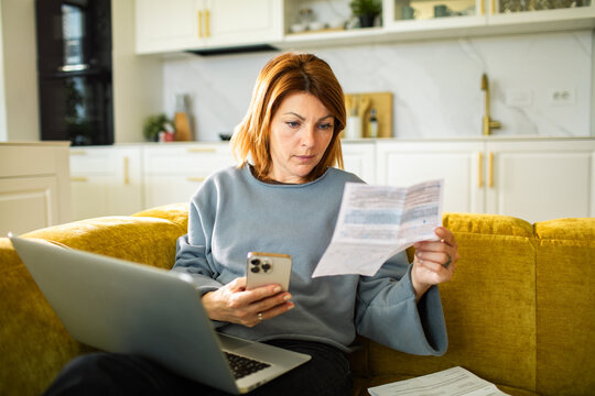 Woman managing household bills with laptop at home