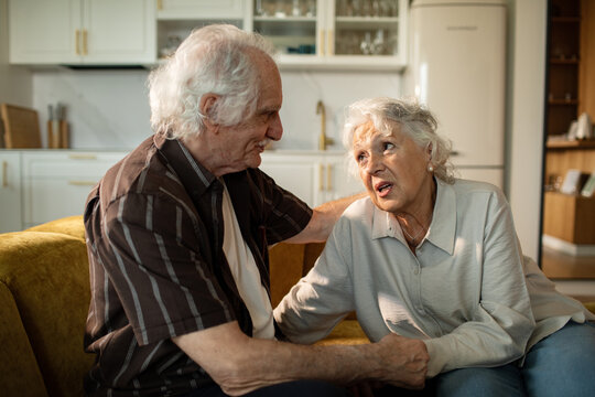 Senior couple sharing emotional conversation on sofa at home