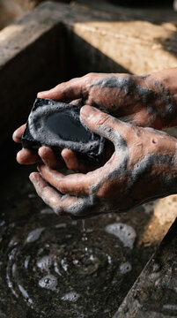 Dirty working hands washing with soap bar in stone sink