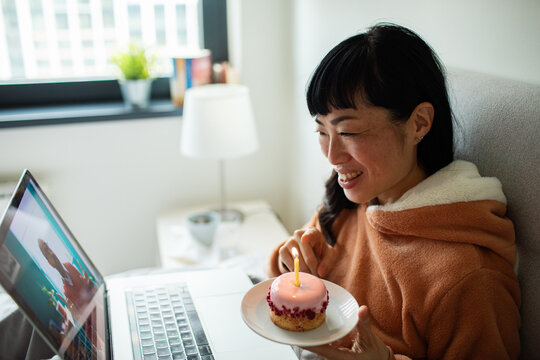 Smiling woman celebrating birthday on video call at home in bed