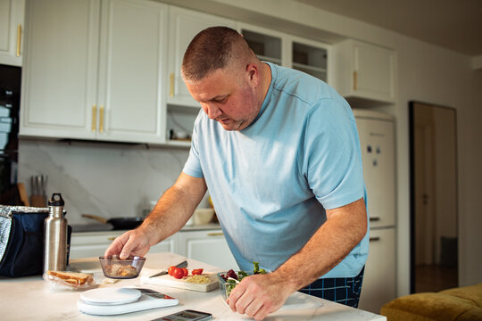 Man preparing healthy lunch with food scale in home kitchen