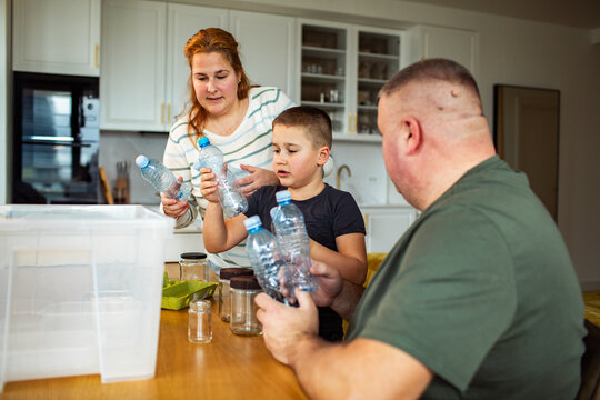 Family sorting plastic bottles for recycling in home kitchen