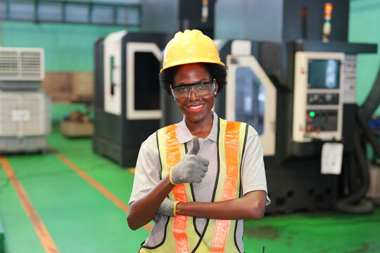 Confident female industrial worker giving thumbs up in modern manufacturing factory