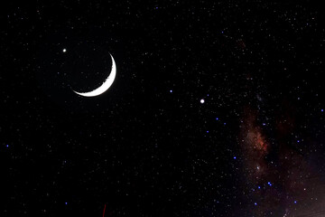 A landscape view of the night sky, featuring stars and a crescent moon. © K.Pornsatid