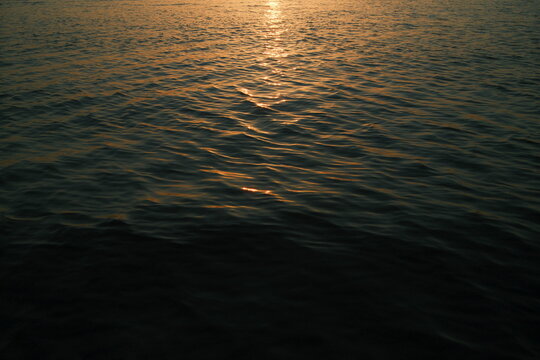 Sunset over a calm ocean with glowing clouds and gentle waves