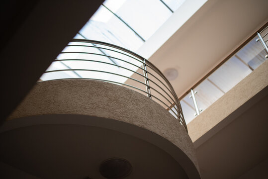 Low-angle view of a curved interior balcony with a metallic railing