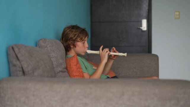 A little boy learns to play the flute at home, practicing with focus and enthusiasm in a cozy, warm setting. A charming scene of early musical exploration, creativity, and childhood growth.