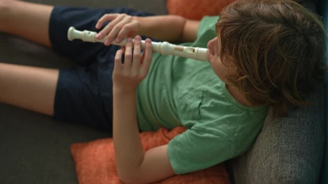 A little boy learns to play the flute at home, practicing with focus and enthusiasm in a cozy, warm setting. A charming scene of early musical exploration, creativity, and childhood growth.