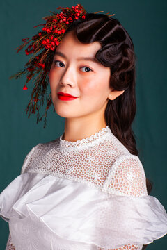 Bridal portrait featuring a vintage-style wavy hairstyle and a red floral accessory.