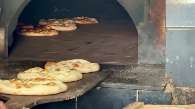 Fresh flatbreads baking in a traditional stone oven. Turkish pide. Turkish pide during Ramadan. 4K video.
