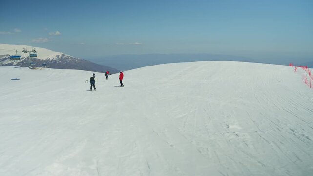 People enjoy skiing and snowboarding on a vast, snow-covered mountain with ski lifts. The clear blue sky provides a perfect backdrop for winter sports activities.