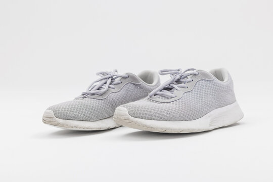 Studio shot of a pair of light grey mesh running sneakers with laces isolated on a seamless white background. Lightweight athletic footwear for running, fitness, and active lifestyle.