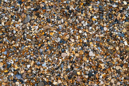 Close-up of naturally rounded flint pebbles and small stones in varied earthy colors on the beach at Horsey Gap on the Norfolk coast, England, creating a richly detailed natural texture.