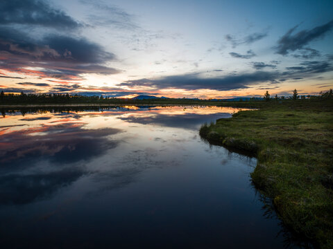 Landscape of lake next to mountain at sunset