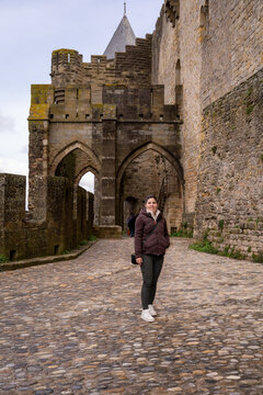 Woman Standing in Medieval Castle Court with Stone Ramparts and Conical Tower