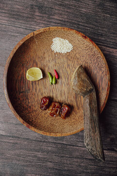 Traditional Indonesian chili paste or sambal ingredients on a wooden mortar and pestle plate, flat lay, top view