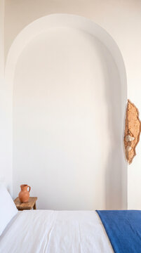 Weathered stone patch revealed inside white archway above coastal bedroom nook