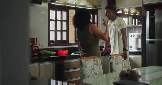 Wife confronting husband during heated discussion in kitchen, man appearing defensive and annoyed, highlighting relationship challenges and emotional strain