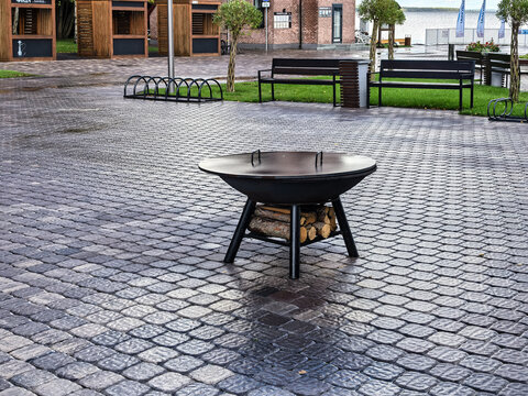 Black Metal Fire Pit with Logs on Cobblestone Patio