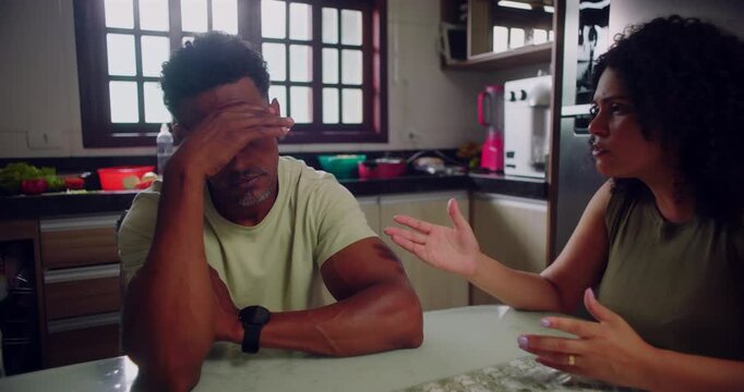 Husband showing frustration and annoyance as wife vents concerns at dining table, tense discussion highlighting relationship issues in kitchen
