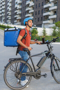 Delivery courier with electric bike waits for order in the city street