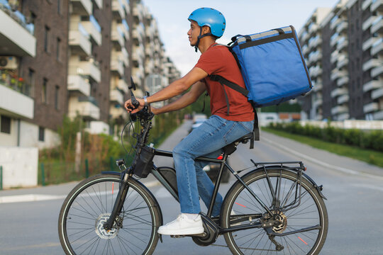 Food delivery service, courier riding electric bicycle with thermal backpack in city