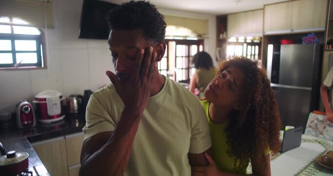 Father rubbing his face in frustration as teenage daughter persists with her demands, highlighting family tension and parenting challenges in the kitchen