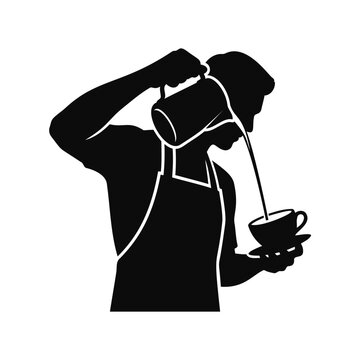 A male barista wearing an apron pouring coffee from a pitcher into a small ceramic cup