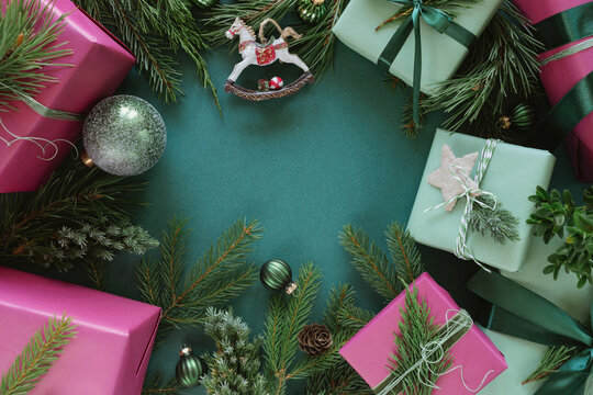 Overhead view of assorted wrapped Christmas gifts decorated with festive foliage on a table, Christmas baubles and a vintage rocking horse ornament