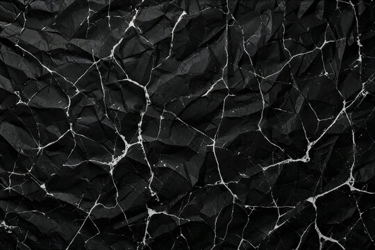 Crumpled black paper texture with white cracked veins, dark abstract wrinkled background, distressed charcoal paper surface for edgy graphic design