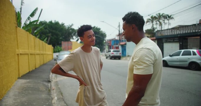 Father of African descent standing with son in an urban street, sharing a meaningful interaction, father guiding with a calm demeanor, symbolizing family bond and connection