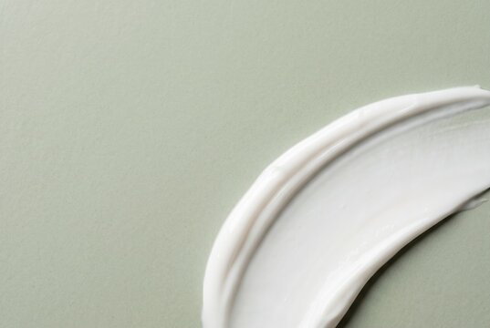 White cosmetic cream sweep on pale sage tile